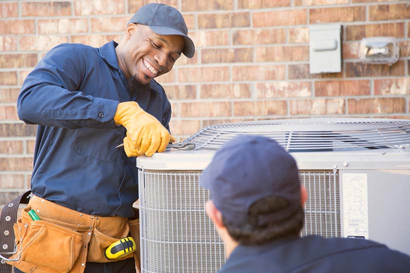 HVAC technicians working on an outdoor air-conditioning unit